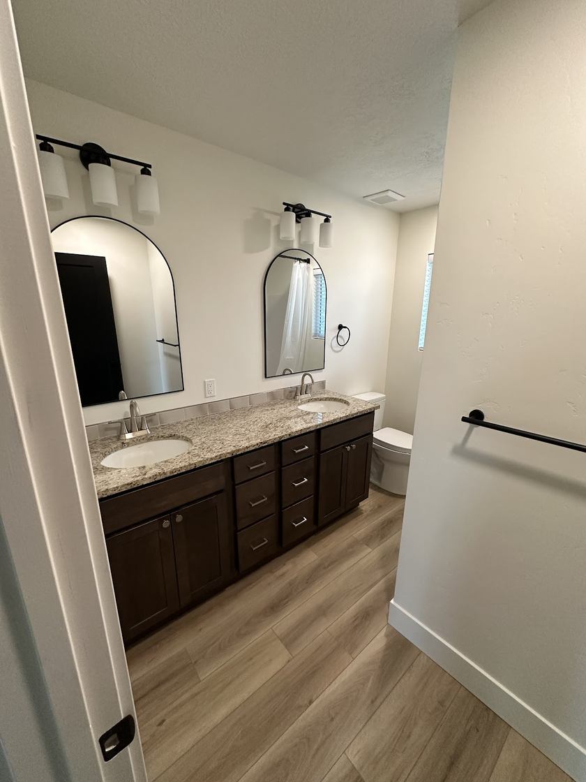 Double vanity · granite + arched mirror — bath remodels by Kovo's Karpentry in Boise, Idaho